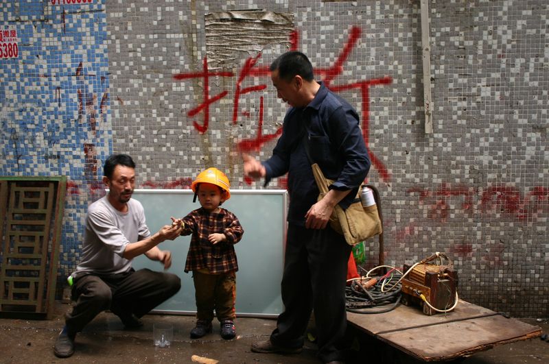 A child plays with two welders, who are getting the kid’s family home ready for demolition