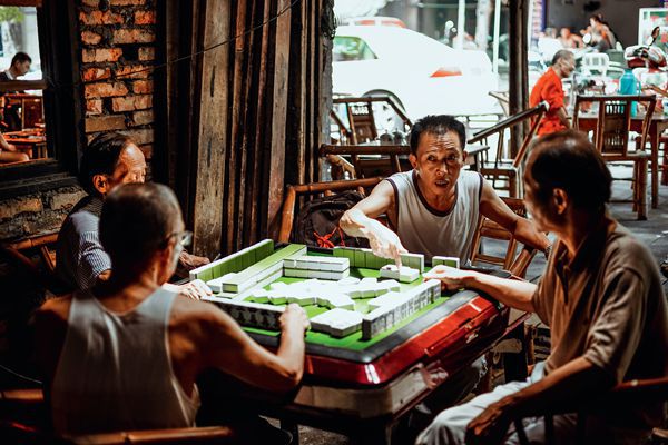 Four Chinese men going about a game of mahjong in a Sichuan teahouse.
