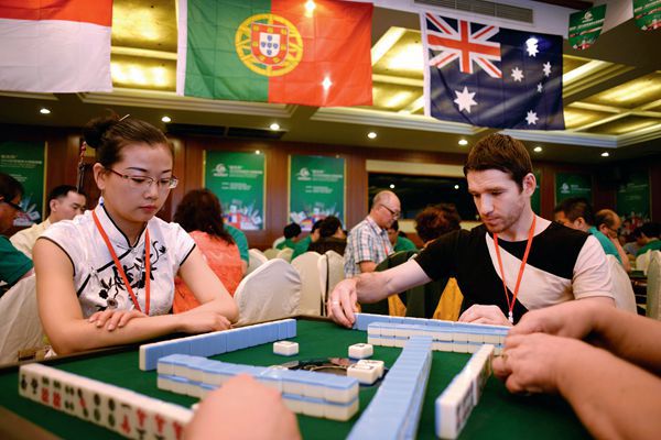 A couple foreigners intently focused on their game of mahjong during the 2014 World Mahjong Masters Tournament in Kunming, Yunnan.