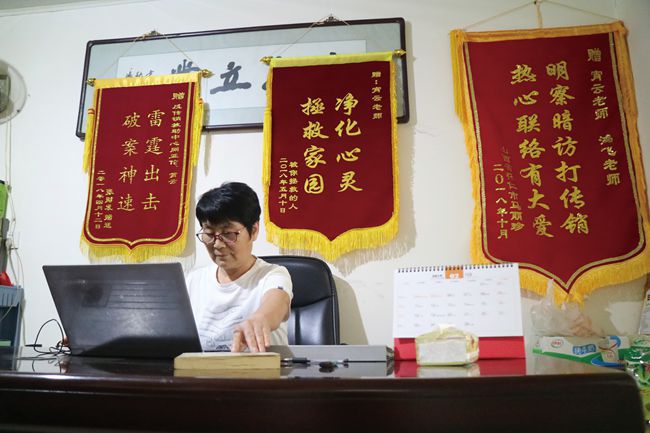 Red banners with warnings about chuanxiao hang behind a woman's desk.